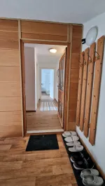 Előszoba fa falburkolattal, fogassal és vendégpapucsokkal