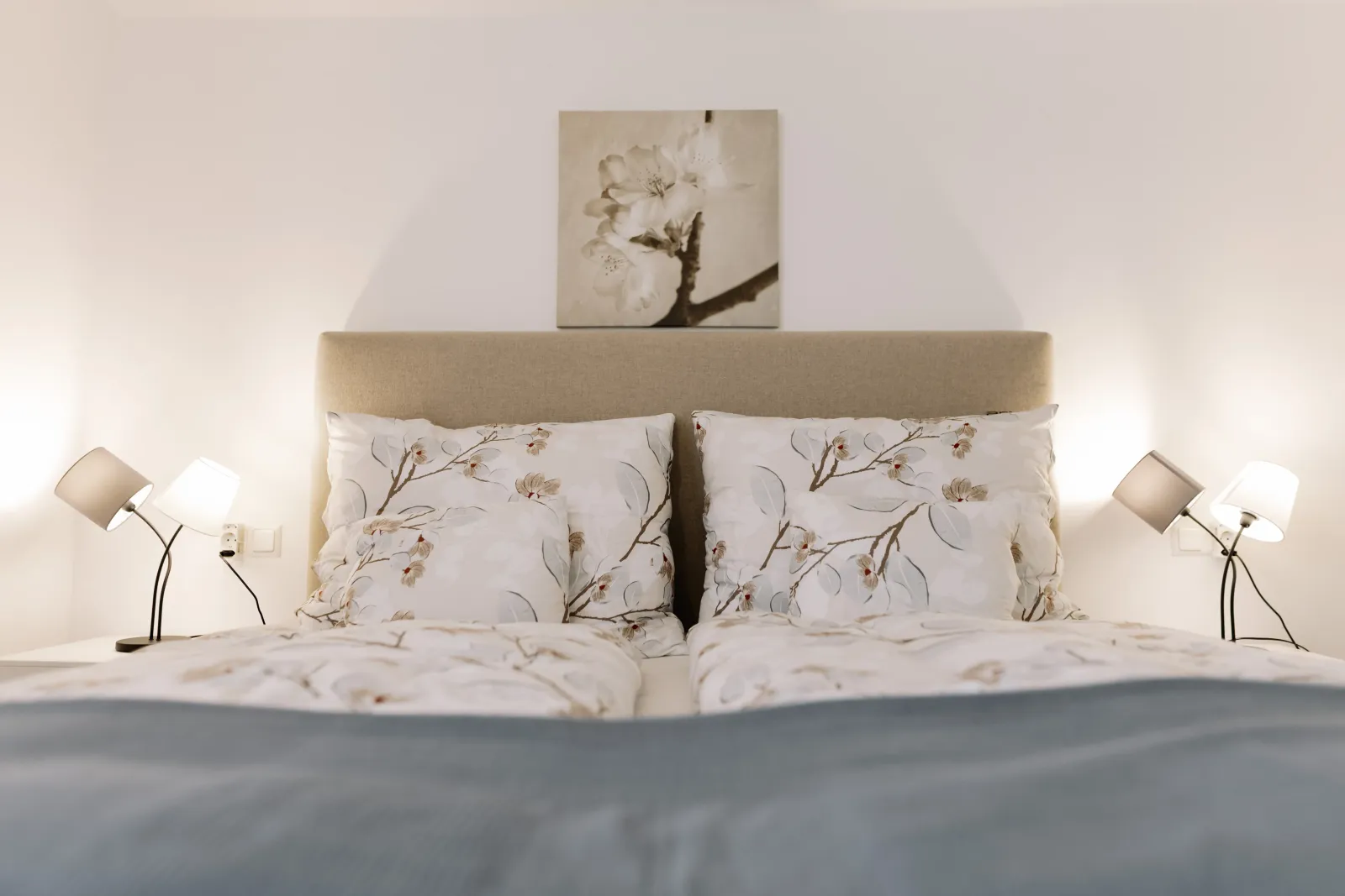 Kényelmes franciaágy virágmintás ágyneművel és olvasólámpákkal